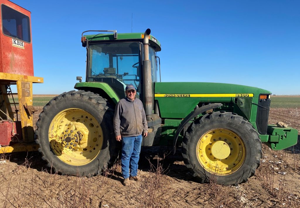 Farmer standing in front of a John Deere tractor.