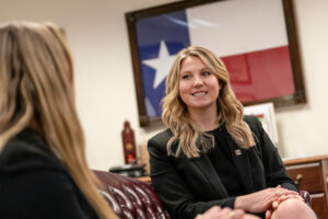 A female political intern sitting in an office in front of a Texas flag