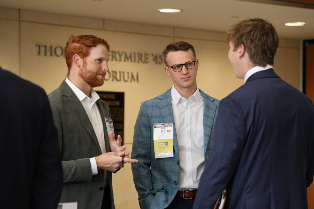 Three men in suits engaged in conversation in a lobby area.