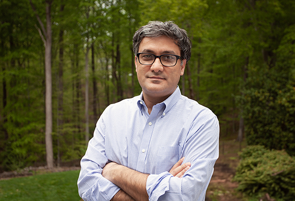 Harun Onder standing in front of trees with his arms folded