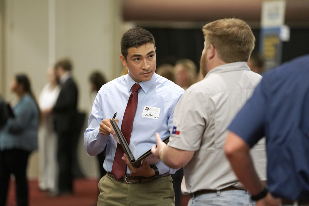 two people speaking while one holds a portfolio