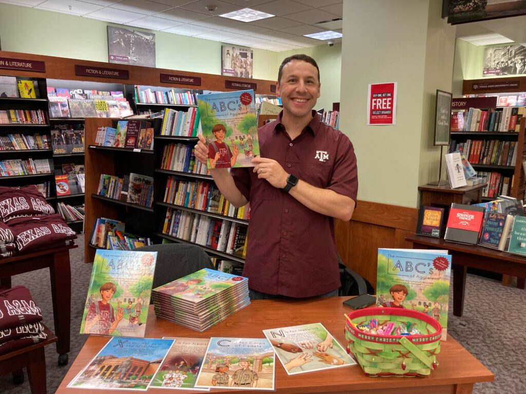 Author Cameron O'Connell holds his book, The ABC's of Aggieland, at a book-signing event.