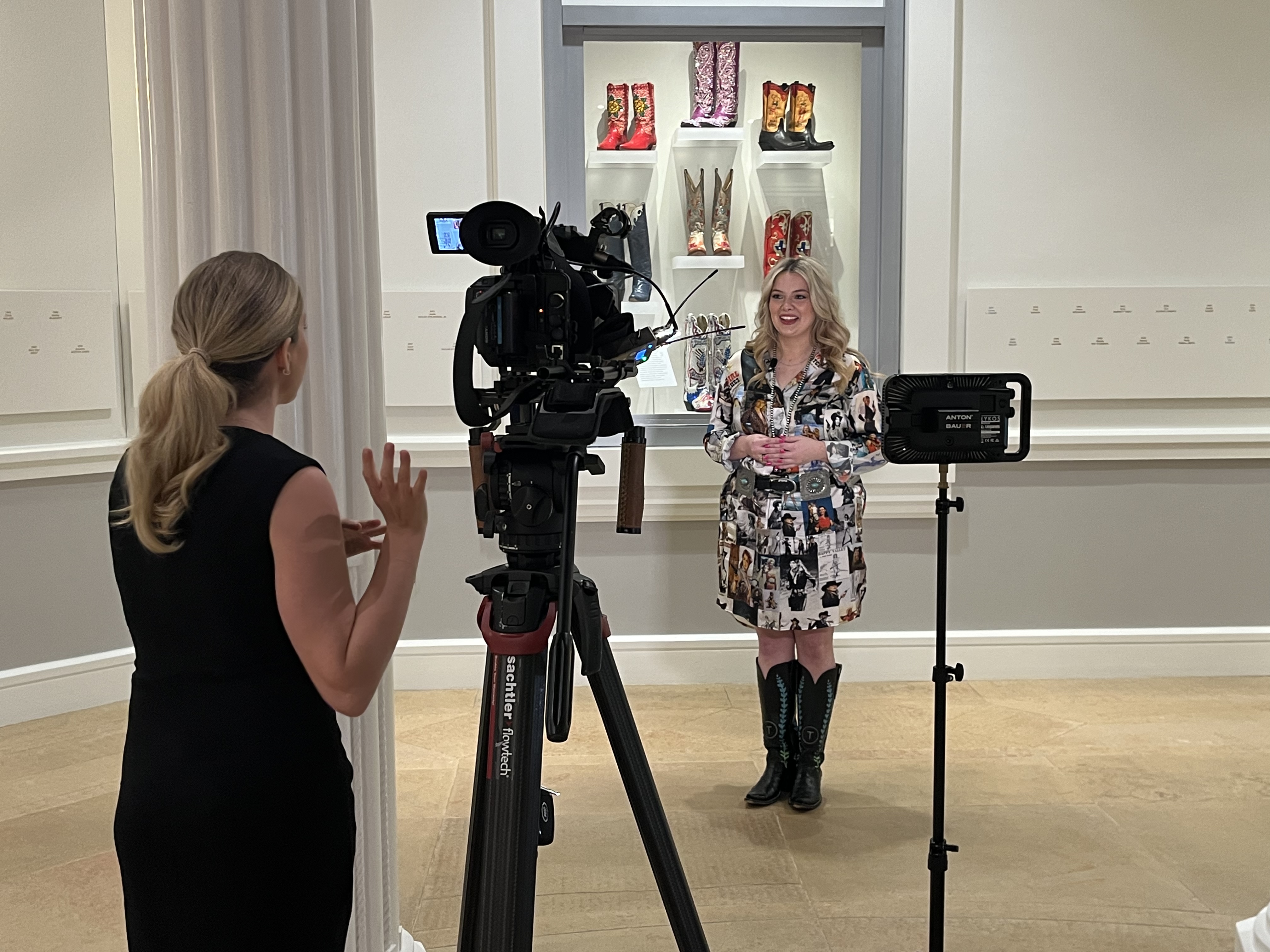 Maggie Terry standing in front of a video camera, being interviewed by a woman behind the camera