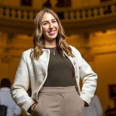 a female student in business attire posing in the Texas state capitol building
