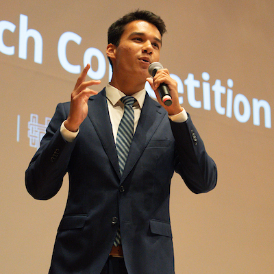 a male student in business attire speaking with a microphone